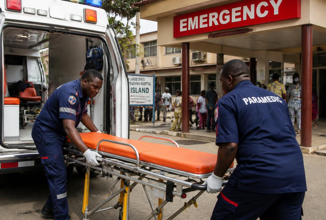 Paramedics preparing an ambulance stretcher at a hospital entrance